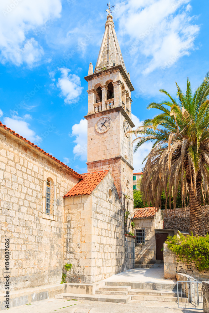 Church building and palm tree against sunny blue sky in Splitska village on Brac island, Croatia Church building and palm tree against sunny blue sky in Splitska village on Brac island, Croatia