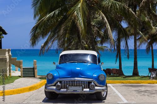 Amerikanischer blauer Buick Oldtimer parkt am Strand unter Palmen in Varadero Cuba - Serie Cuba Reportage