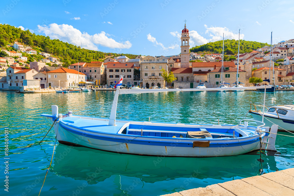 Fishing boat in Pucisca port with beautiful church in background, Brac island, Croatia