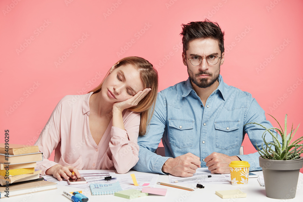 Angry strict young stylish attractive male being annoyed with his female companion who fell asleep at working place, didn`t manage to finish work, should do everything alone, has many troubles Angry strict young stylish attractive male being annoyed with his female companion who fell asleep at working place, didn`t manage to finish work, should do everything alone, has many troubles