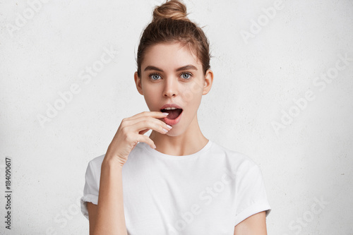 Amazed young female model with pleasant appearance watches with bated breath interesting melodrama, worries about main characters, expresses true emotions and feelings on camera isolated over white photo