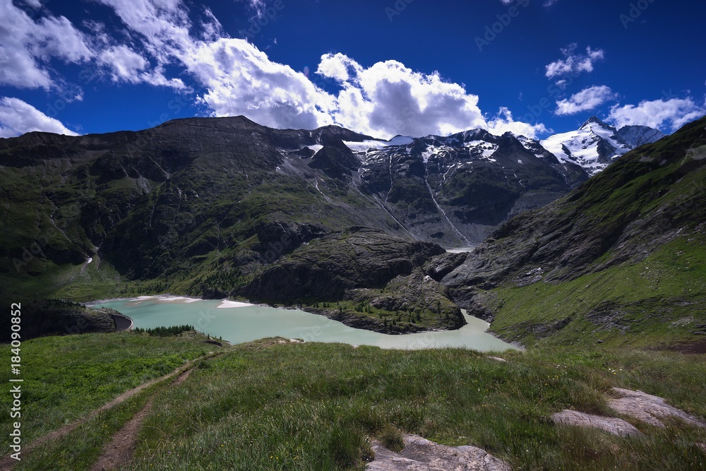 High Alpine lake or dam and meadows near Grossglockner mountain in Austria catching water from Pasterze glacier during the summer melting. Picture taken in Austria in Tirol tauern region. 