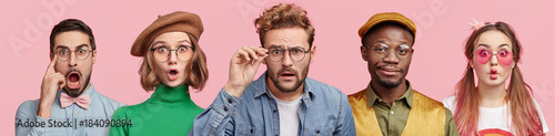 Composition of five different people wear spectacles, look with surprised expression, beig from various nations, express shock and disbelief. Women and men stand in row isolated on pink background