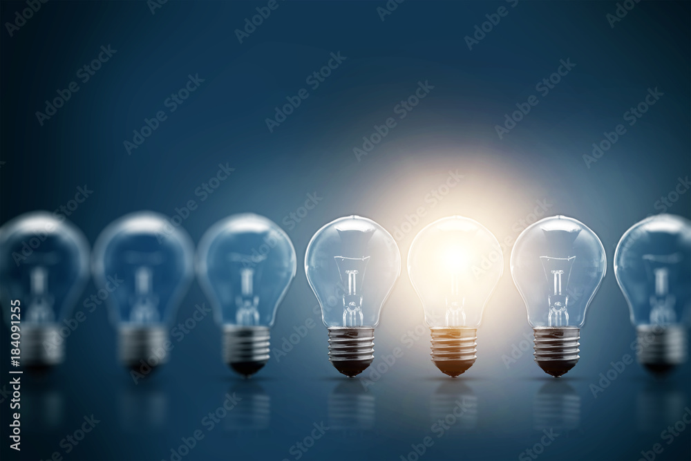 A series of electric light bulbs, only one glows, against a dark background. The concept of several attempts, one successful. A successful idea. A series of electric light bulbs, only one glows, against a dark background. The concept of several attempts, one successful. A successful idea.