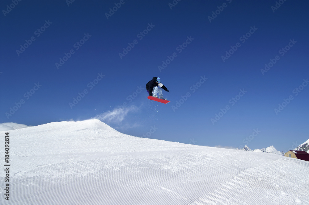 Snowboarder jump in terrain park at ski resort on sunny winter day