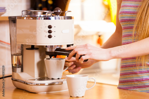 Canvastavla Woman in kitchen making coffee from machine