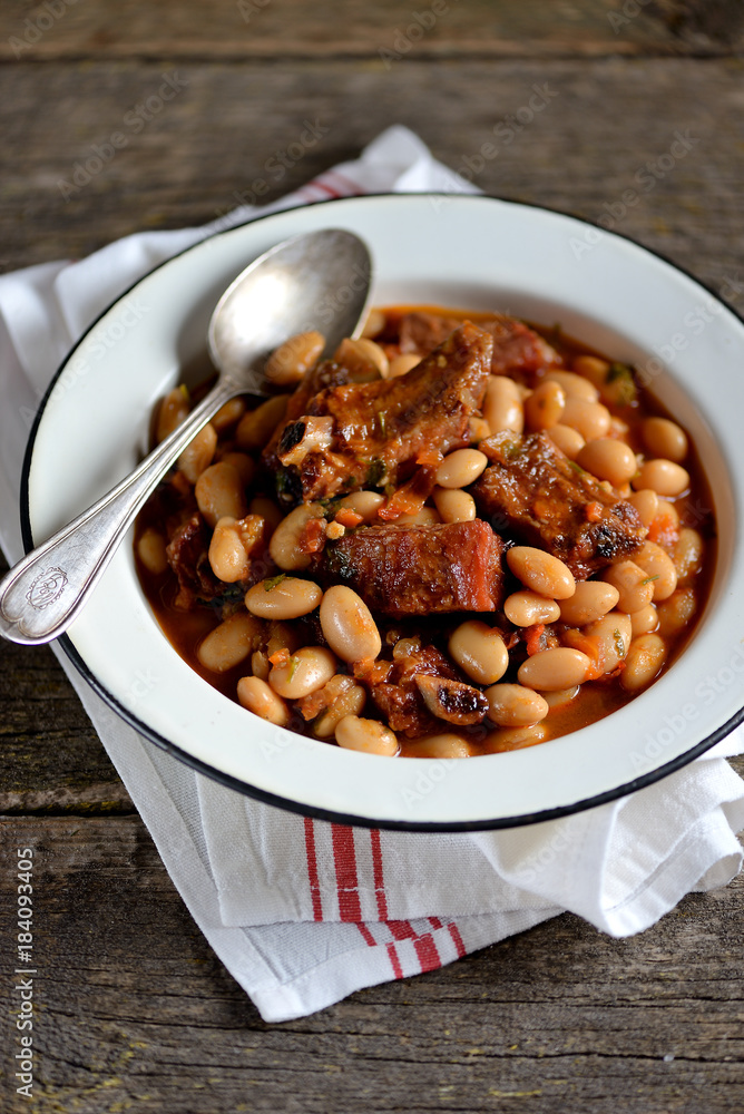 White beans stewed with smoked ribs, onions, carrots, garlic, red paprika, tomatoes and parsley. White beans stewed with smoked ribs, onions, carrots, garlic, red paprika, tomatoes and parsley.