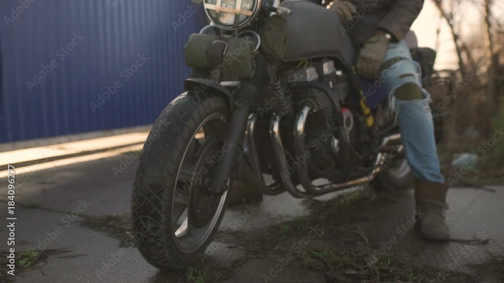 Motorcyclist sits on an old cafe-racer motorcycle, autumn background Motorcyclist sits on an old cafe-racer motorcycle, autumn background