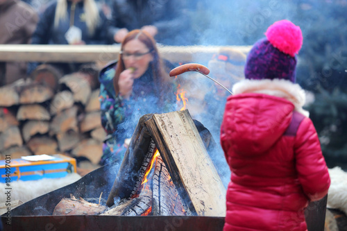 Dziewczynka piecze kiełbasę przy ognisku z mamą.
