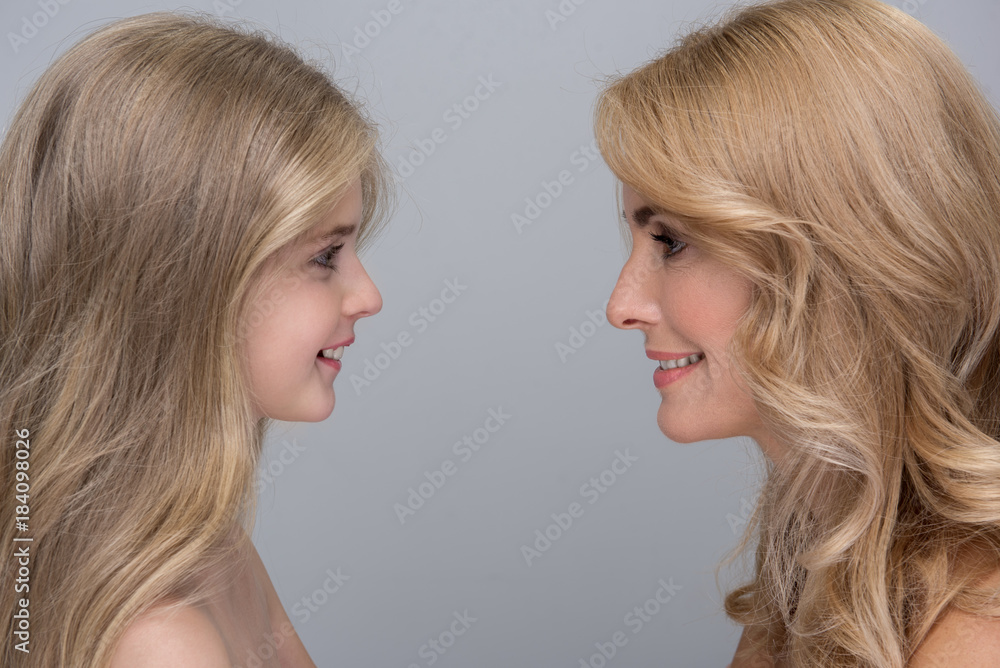 My little princess. Side view profile of cheerful mother and her pretty daughter are standing and looking at each other with love. They are feeling happiness while spending time together. Isolated My little princess. Side view profile of cheerful mother and her pretty daughter are standing and looking at each other with love. They are feeling happiness while spending time together. Isolated