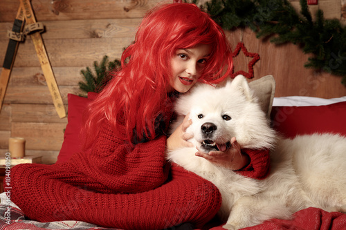 Winter dog holiday and Christmas. A girl in a knitted sweater and with red hair with a pet in the studio. Christmas woman with a beautiful face and pet. photo