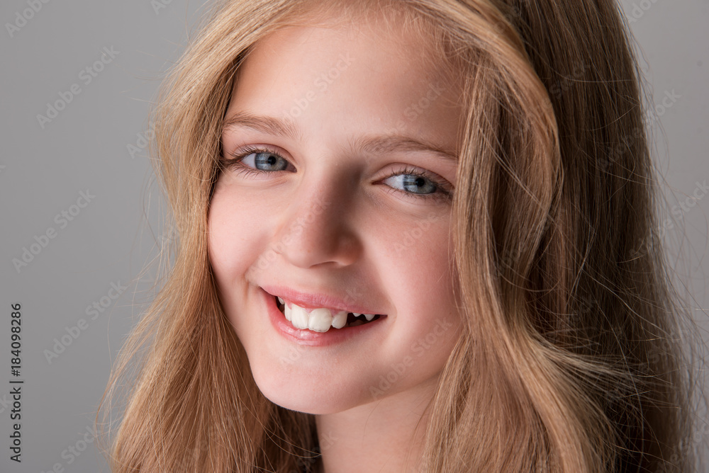 Happy smile. Close-up portrait face of cheerful attractive little girl is standing and looking at camera with joy. Isolated background Happy smile. Close-up portrait face of cheerful attractive little girl is standing and looking at camera with joy. Isolated background