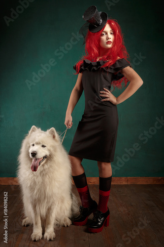 Winter dog holiday and Christmas. Girl in a black dress and with red hair with a pet in the studio. Christmas woman with a beautiful face and pet. photo