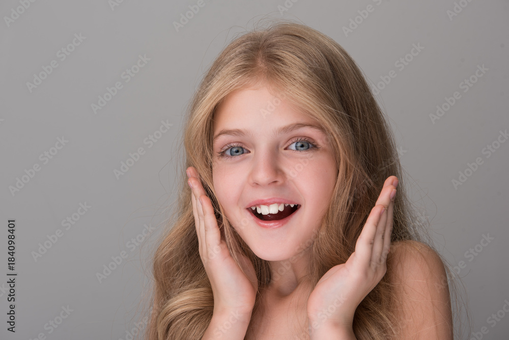 Cannot believe. Close-up portrait of surprised lovely girl is standing and smiling while looking at camera with astonishment. She is holding hands by her face. Isolated background Cannot believe. Close-up portrait of surprised lovely girl is standing and smiling while looking at camera with astonishment. She is holding hands by her face. Isolated background