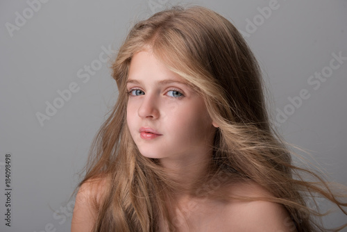 Lovely pretty girl is looking at camera pensively while enjoying wind in her long hair. Isolated background