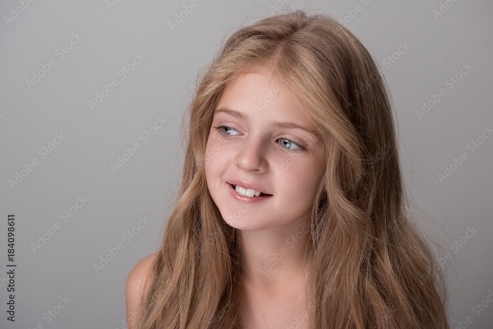 Dreaming about future. Cheerful cute small girl is looking aside with slight smile. Isolated background Dreaming about future. Cheerful cute small girl is looking aside with slight smile. Isolated background