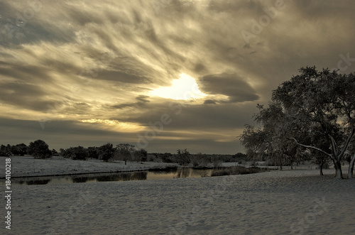 Winter snow covered field with pond and wide angle dramatic clouds
