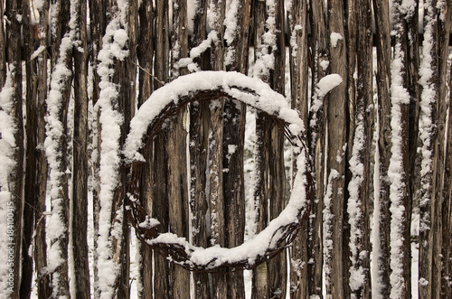 Wood branch fence with wreath covered with snow