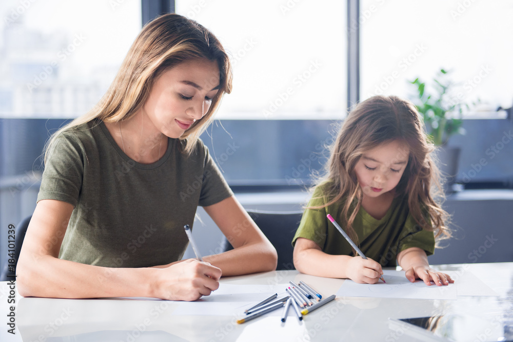 Portrait of cheerful asian family is drawing together at home. They are holding colorful pencils and looking at paper with concentration Portrait of cheerful asian family is drawing together at home. They are holding colorful pencils and looking at paper with concentration