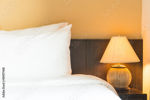 White comfortable pillow on bed with light lamp