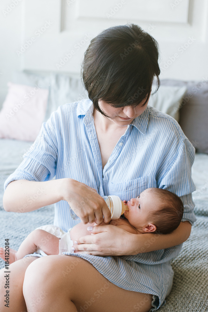 feeding the newborn with a mixture in a bottle. artificial nutrition. mother's love and warmth feeding the newborn with a mixture in a bottle. artificial nutrition. mother's love and warmth