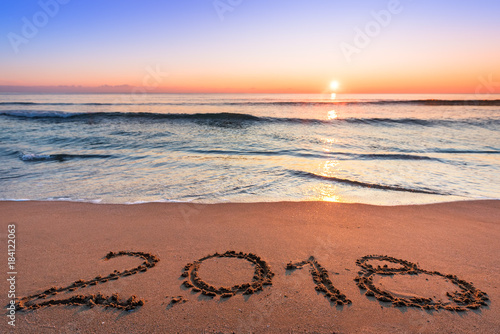 Number 2018 written on seashore sand at sunrise.