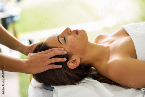 Young smiling woman receiving a head massage in a spa center.