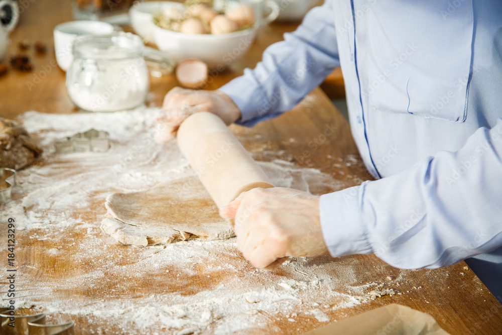 Woman in kitchen making Christmas gingerbread cookies 