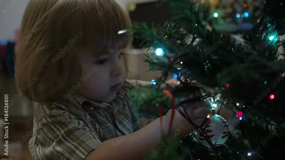 Cute little boy decorates the Christmas tree. Cute little boy decorates the Christmas tree.