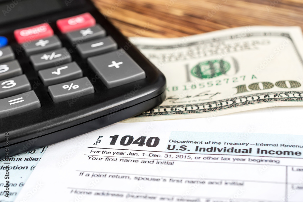 Calculator with one hundred dollar bill on the tax form. Calculator with one hundred dollar bill on the tax form.