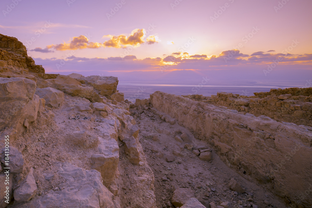Obraz premium Beautiful purple sunrise over Masada fortress. Ruins of King Herod's palace in the Judaean Desert