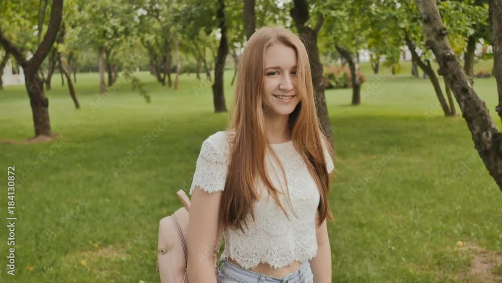 Young beautiful female student with long hair with a backpack on her back is walking in the park. Rest during study. Young beautiful female student with long hair with a backpack on her back is walking in the park. Rest during study.