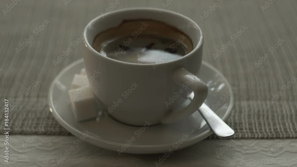 Close up white cup black coffee with sugar and spoon on saucer standing on table Close up white cup black coffee with sugar and spoon on saucer standing on table