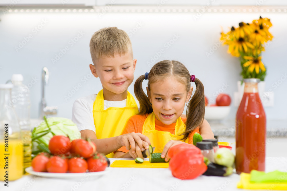 Children cut cucumbers for vegetable salad Children cut cucumbers for vegetable salad