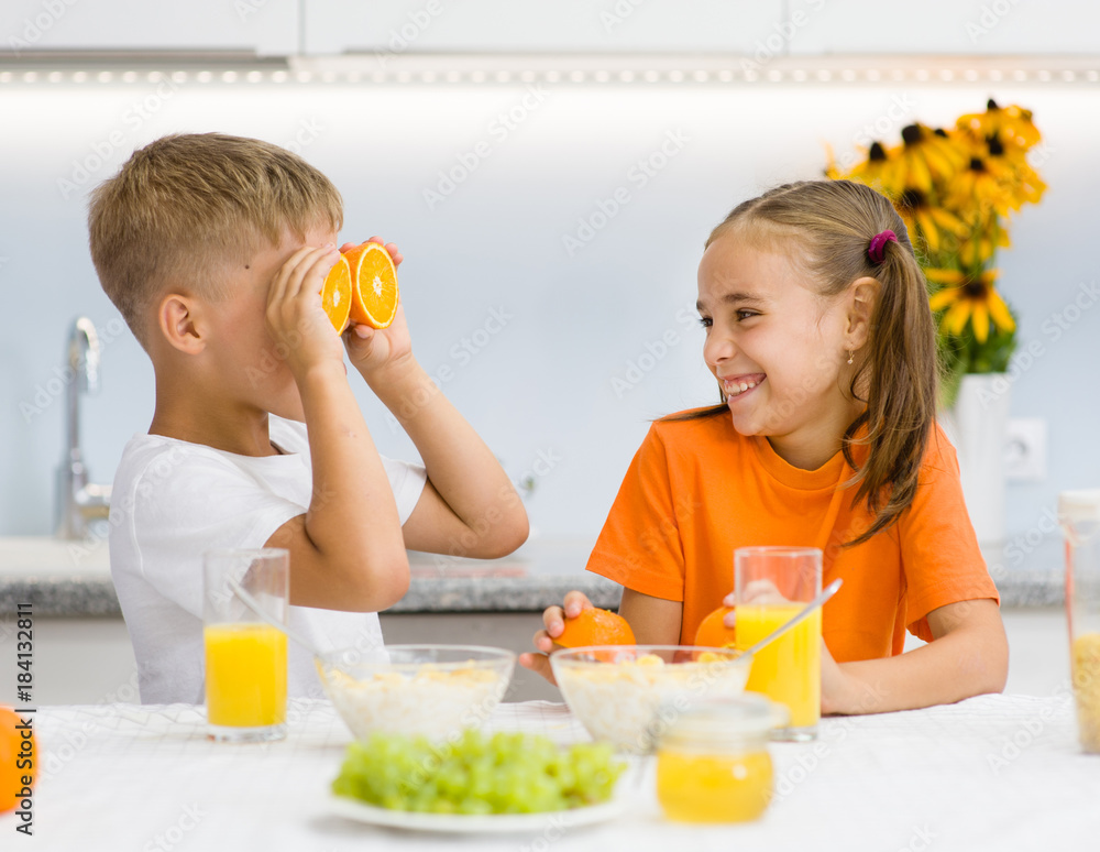 Girl laughs at her brother with orange before his eyes like in glasses Girl laughs at her brother with orange before his eyes like in glasses