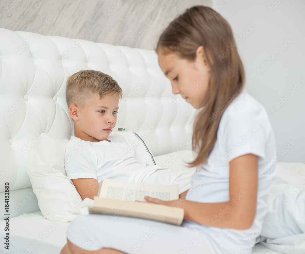 Little girl reads the book to the sick brother Little girl reads the book to the sick brother