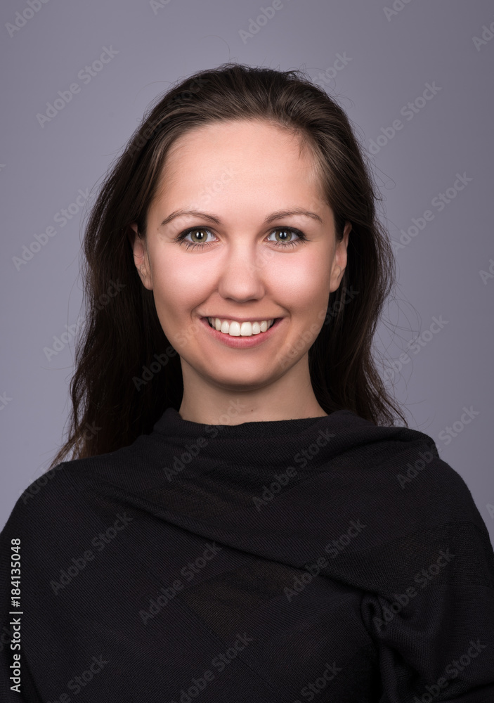 Fototapeta premium Natural portrait of young woman in black on a dark gray background. The woman smiles