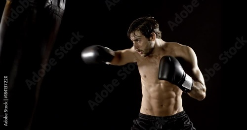 Athletic male working out using heavy punching bag. Slow motion.
