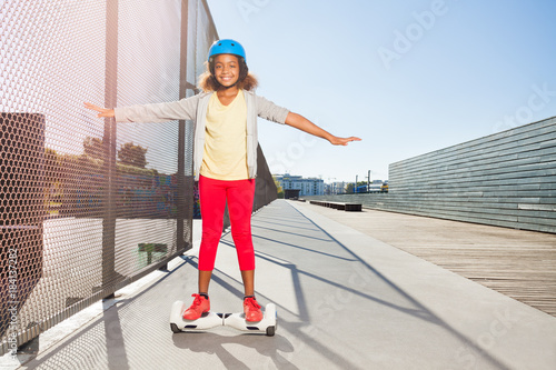 African girl riding hoverboard on the side walk