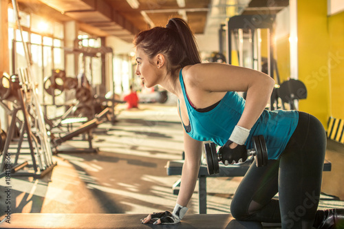 Sensual young woman with exercising with dumbbell in the gym.