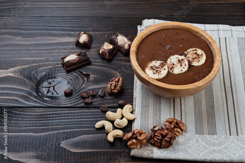 Homemade chocolate banana smoothie on a bowl on wooden background