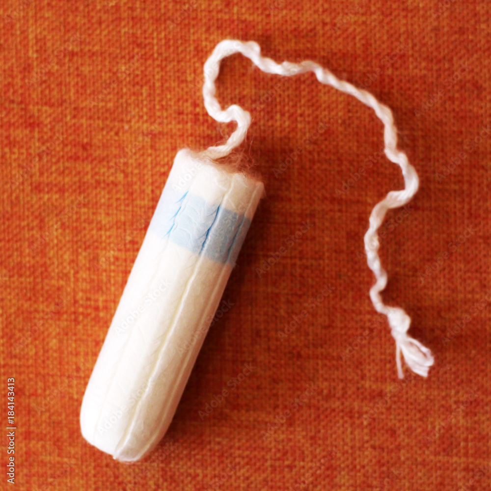 one female hygienic tampon on orange background one female hygienic tampon on orange background