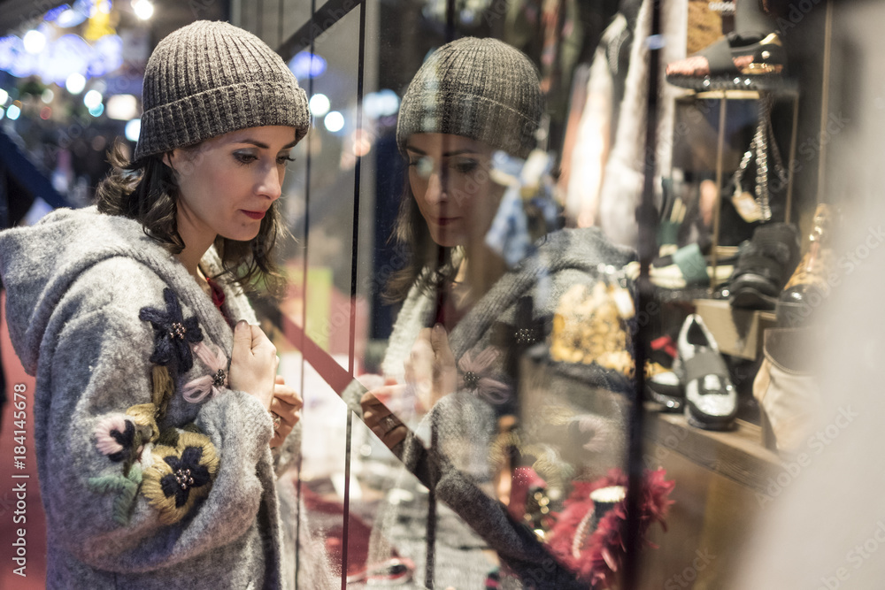 Woman looking shop store fashion window in winter nights looking for some clothes