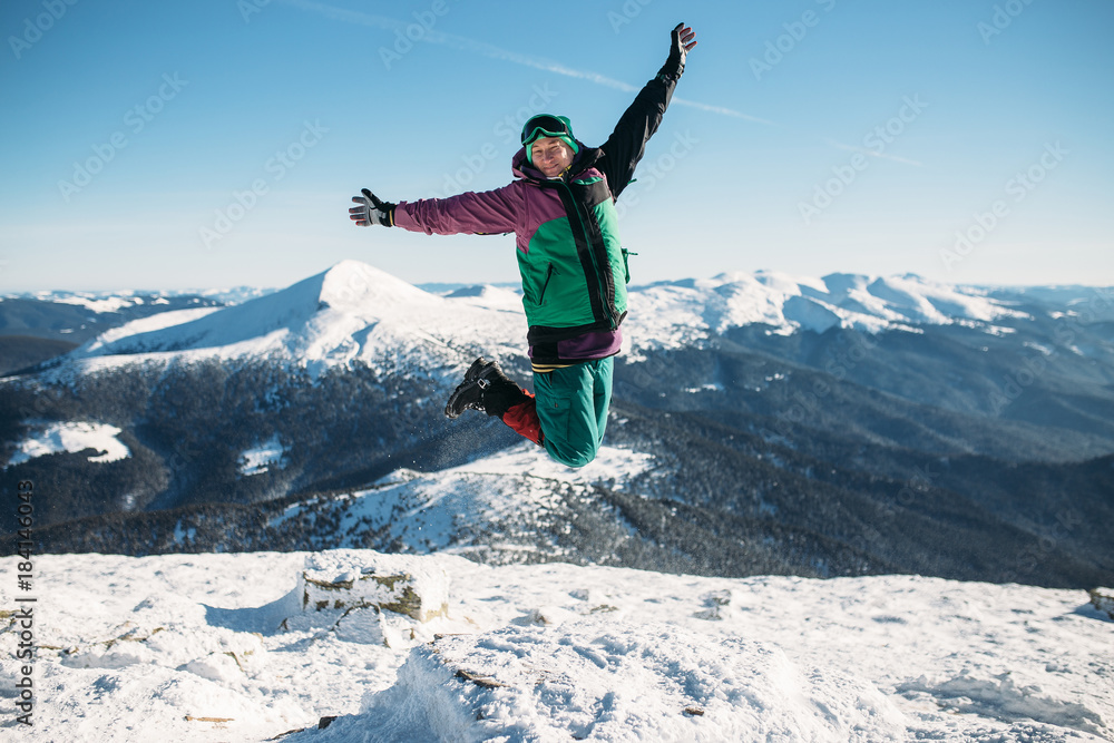 A man is jumping on top of a mountain