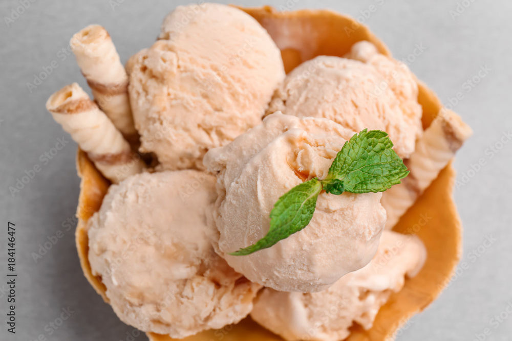 Waffle bowl with caramel ice cream on grey background, closeup Waffle bowl with caramel ice cream on grey background, closeup