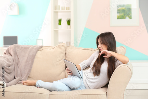 Young woman with tablet on sofa at home