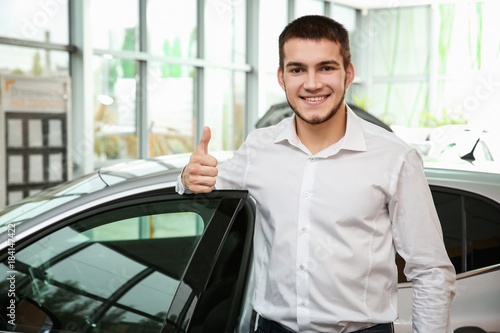 Handsome car salesman showi...