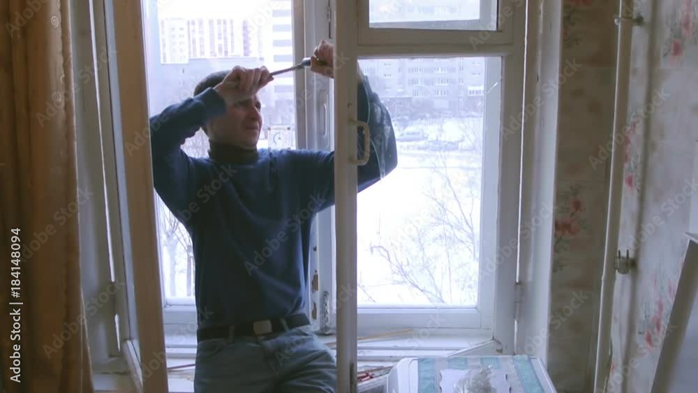 Man repairs wood window. Replace broken glass on window Man repairs wood window. Replace broken glass on window