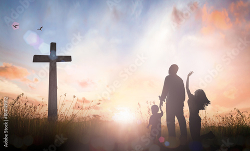 Fotografia Family worship concept: Silhouette father mother and son looking for the cross on autumn sunrise background