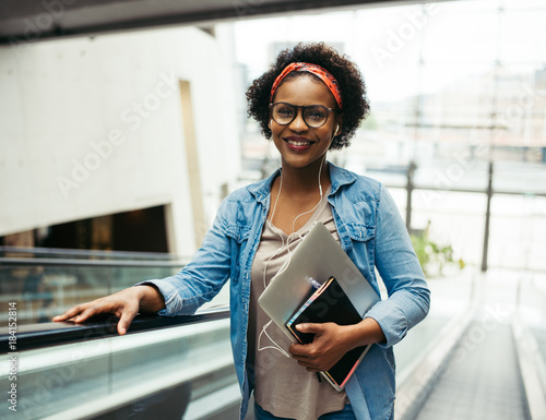 Smiling African entrepreneur riding an escalator in an office bu photo